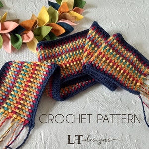 May include: A crochet scarf with a multi-colored bobble stitch pattern and navy blue edging. The scarf has long fringe tassels on each end. The text "CROCHET PATTERN LT designs" is visible in the image.