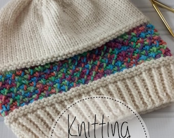 May include: Cream-colored knitted hat with a multicolored band and a fluffy pom-pom. The hat features a ribbed brim and a textured stitch pattern. A ball of yarn and knitting needles are in the background. The text "Knitting Pattern" is in a circle.