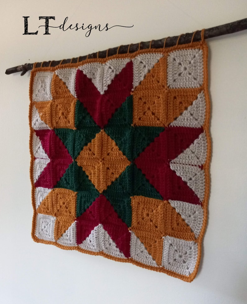 May include: A crocheted wall hanging with a star design in shades of red, green, orange, and white. The hanging is attached to a branch.