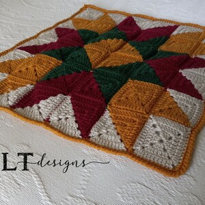 May include: A crocheted throw blanket with a star pattern in shades of red, green, beige, and gold. The blanket is made with a variety of stitches and textures, creating a unique and interesting design.