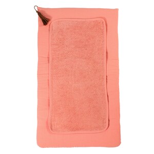 Könnte beinhalten: Eine korallenrosa Wickelunterlage mit einem weichen, saugfähigen Handtucheinsatz. Die Unterlage hat oben einen Quasten-Detail.