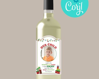Könnte beinhalten: Eine Flasche Weißwein mit einem roten und grünen Weihnachts-Etikett, das ein Foto eines Kindes und den Text "OUR CHILD might be the REASON YOU DRINK so please ENJOY this bottle on us MERRY CHRISTMAS The Thompsons" zeigt.