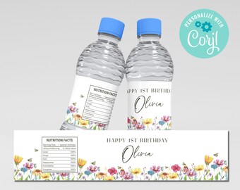 Op de afbeelding: Waterfleslabels met een bloemenontwerp en de tekst "Happy 1st Birthday Olivia" en "Nutrition Facts" met een lijst van items zoals liefde, knuffels, plezier, geluk en vriendschap. De labels zijn gedrukt op wit papier met een lichtblauwe achtergrond.