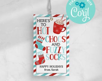 Pode incluir: Etiqueta de presente listrada em vermelho e branco com uma caneca de chocolate quente azul e branca, meias listradas em vermelho e branco e o texto "Here's to hot chocs and fuzzy socks. Happy Holidays from, Sarah."