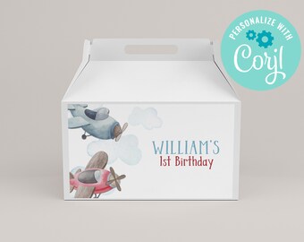 May include: White favor box with a blue and red airplane design. The box has a handle and says "William's 1st Birthday" on the front.