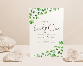 May include: A white invitation card with green shamrock designs around the border. The text reads "Charlie is a lucky One" and includes details for a birthday party.