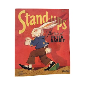 May include: A vintage book cover featuring a white rabbit in a blue jacket and brown pants. The title is "Stand-Ups" and the subtitle is "The tale of Peter Rabbit". The cover is red with yellow lettering.