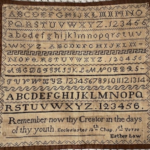 May include: A brown sampler with a beige background featuring the alphabet, numbers, and the quote "Remember now thy Creator in the days of thy youth. Ecclesiastes sath Chap. st Verse. Esther Law".