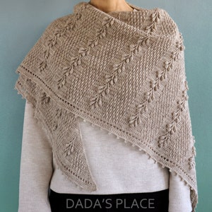 May include: A beige crochet shawl with a delicate leaf pattern and a scalloped edge. The shawl is draped over a person's shoulders.