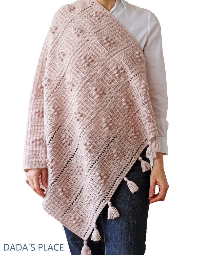 Peut inclure: Un ch&acirc;le en crochet rose avec un motif en losange et des glands. Le ch&acirc;le est drap&eacute; sur les &eacute;paules d'une personne.