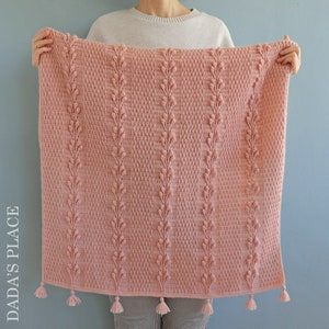 May include: A pink crocheted blanket with a leaf pattern and tassels.