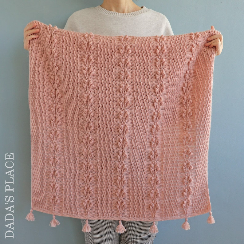 May include: A pink crocheted blanket with a leaf pattern and tassels.