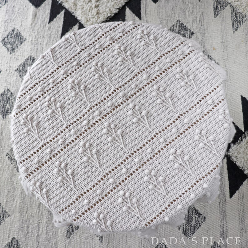 May include: A white crocheted blanket with a textured pattern of small raised dots. The blanket is circular and has a delicate, lacy look.
