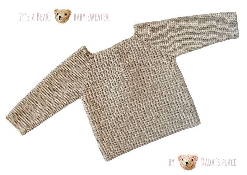 May include: A beige baby sweater with a ribbed texture. The sweater has a round neckline and long sleeves. The text "It's a Bear!" and "Baby Sweater" is printed above the sweater. The text "By Dada's Place" is printed below the sweater.
