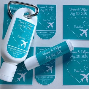 May include: A set of turquoise blue wedding favor labels with white text and a white airplane graphic. The labels read "Viviana & Delfino Aug 30, 2015 Punta Cana". The labels are designed for sunscreen lotion bottles and lip balm tubes.