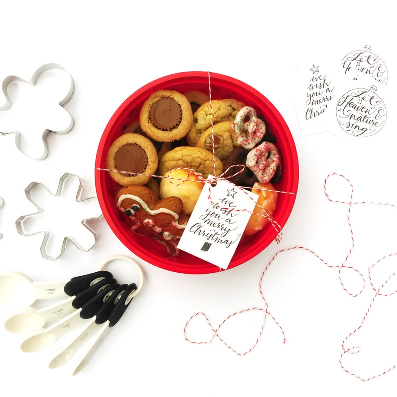 May include: A red bowl filled with assorted Christmas cookies, tied with twine and a gift tag that reads "We wish you a merry Christmas".