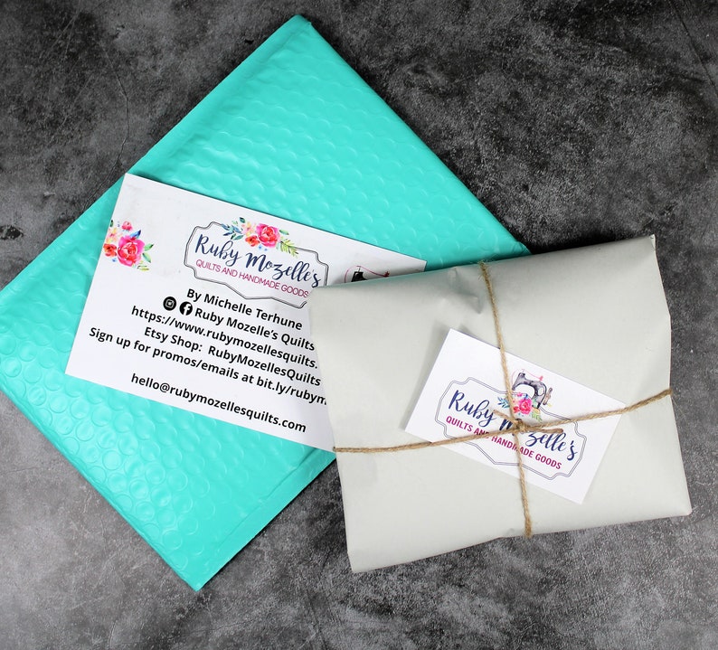 May include: A turquoise bubble mailer with a business card that reads "Ruby Mozelle's Quilts and Handmade Goods" and includes contact information. A second business card with the same text is tied with twine to a white package.