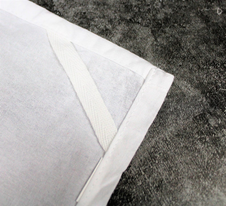 May include: Close-up of a white fabric with a white seam tape sewn along the edge.