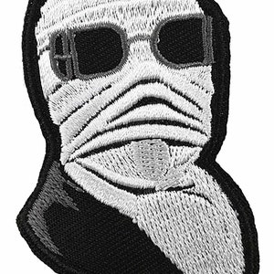 Puede incluir: Parche bordado que representa una imagen en blanco y negro de una figura con vendas y gafas oscuras. El parche tiene un borde negro y está diseñado para aplicarse en ropa o accesorios.