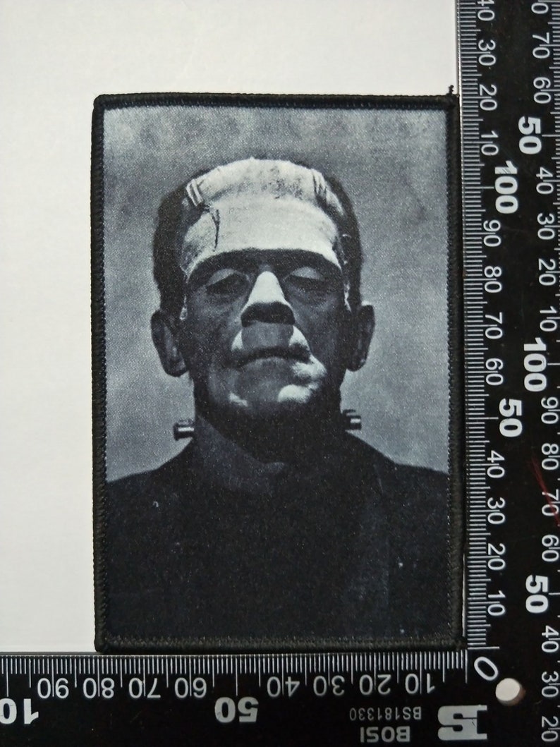 Pu&ograve; includere: Immagine in bianco e nero del mostro di Frankenstein su una toppa di tessuto nero. La toppa misura circa 10 cm per 12,5 cm.