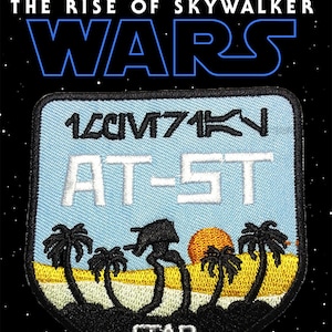 Op de afbeelding: Geborduurde patch met de tekst "STAR WARS" en "THE RISE OF SKYWALKER". De patch heeft een lichtblauwe achtergrond met de tekst "AT-5T" en een illustratie van een woestijnlandschap met palmbomen en een walker.