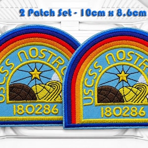 May include: A set of two embroidered patches measuring 10cm x 8.6cm. Each patch is semi-circular with a rainbow border, featuring the text USCSS NOSTROMO and 180286 in yellow. The design includes a yellow star, a brown planet, and a yellow ringed planet against a light blue background.