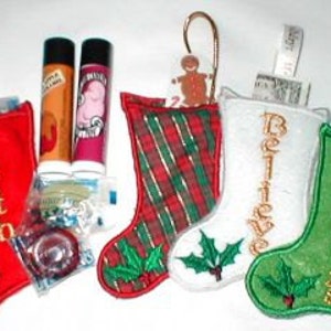 May include: Four small red, green, and white Christmas stockings with holly embroidery. The stockings are filled with small gifts, including lip balm, candy, and a gingerbread ornament. The stockings are personalized with the words "Faith", "Believe", and "Merry Christmas".