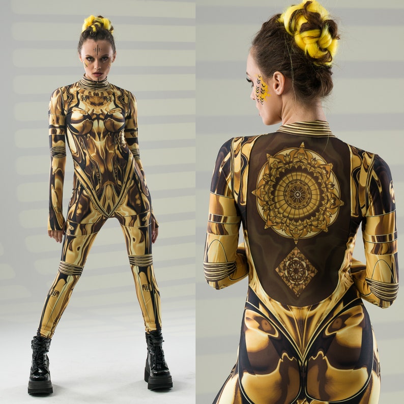 May include: Two women wearing gold and black patterned jumpsuits with geometric designs. One woman is wearing a yellow hairpiece and the other has a yellow hair clip.