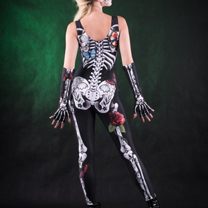 May include: A woman wearing a black skeleton costume with butterflies and roses. The costume is a full-body jumpsuit with a skeleton design and floral accents.