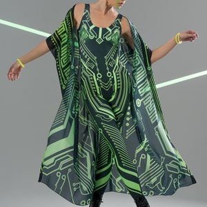 May include: A woman wearing a black and green jumpsuit with a circuit board pattern. She is also wearing a matching black and green kimono with a circuit board pattern. The kimono is open in the front and the woman is standing with her arms outstretched.