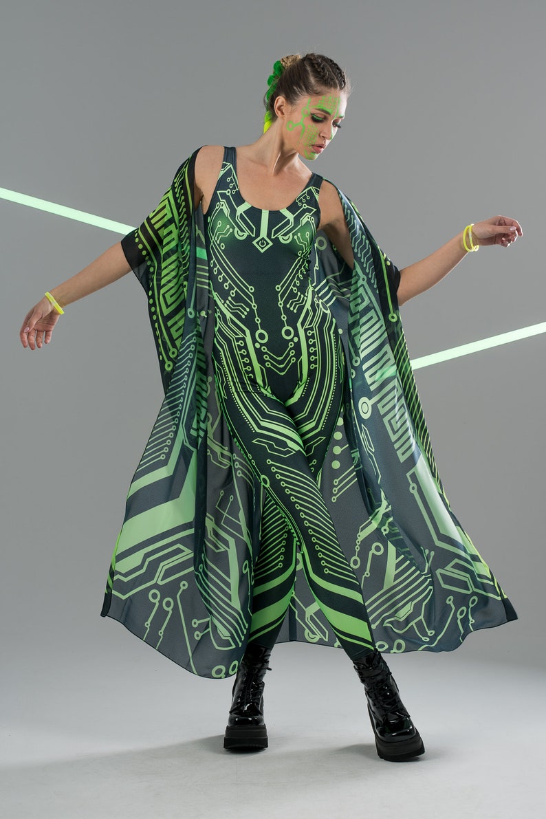 May include: A woman wearing a black and green jumpsuit with a circuit board pattern. She is also wearing a matching black and green kimono with a circuit board pattern. The kimono is open in the front and the woman is standing with her arms outstretched.