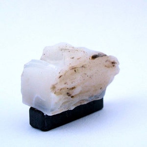 May include: A white and brown mineral specimen on a black base.