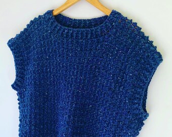 Könnte beinhalten: Ein blaues, ärmelloses Häkeltop mit einem strukturierten Muster. Das Top hat einen runden Ausschnitt und einen leicht asymmetrischen Saum.