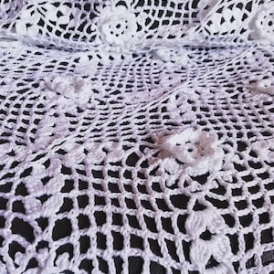 May include: White crocheted doily with a delicate floral pattern.