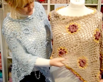 May include: Two crocheted shawls, one light blue and one beige with yellow and pink accents. The shawls are displayed on a mannequin and a person is holding the beige shawl.