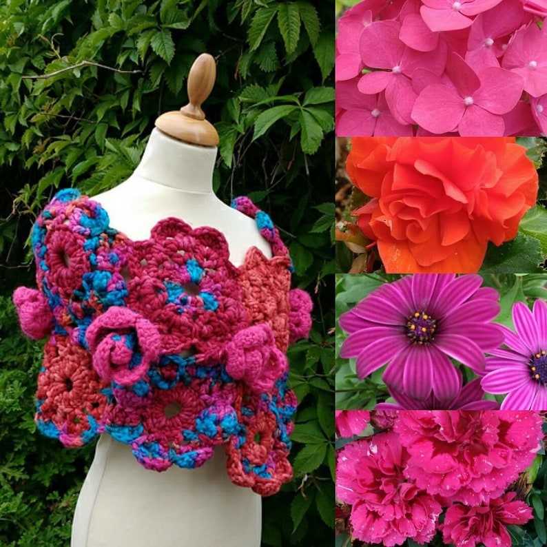 May include: A crochet shawl featuring a floral pattern in shades of magenta, pink, and bright blue, displayed on a mannequin. The design consists of interconnected circular motifs and three-dimensional flower embellishments throughout the garment.