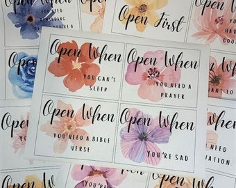 Può includere: Un set di 10 carte con disegni floreali ad acquerello e il testo "Open When" seguito da una frase. Le frasi includono "Hai bisogno di una preghiera", "Sei stressato", "Hai bisogno di un versetto biblico", "Non riesci a dormire", "Sei triste", e "Hai bisogno di una passeggiata nel viale dei ricordi".