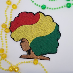 May include: Embroidered patch of a woman with an afro hairstyle in red, yellow, and green colors. The woman is wearing a gold hoop earring.