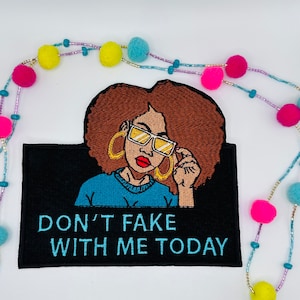 May include: Embroidered iron-on patch with a black background featuring a cartoon woman with brown hair wearing blue sunglasses and a blue shirt. The text "DON'T FAKE WITH ME TODAY" is written in white.