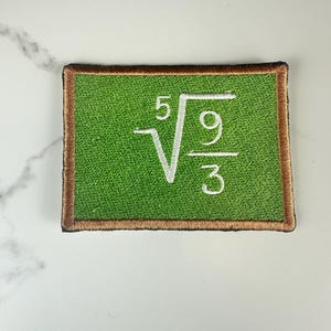 May include: A rectangular embroidered patch featuring a bright green center with a brown border. The center displays a white mathematical expression consisting of a fifth root symbol over a fraction with nine in the numerator and three in the denominator.