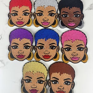 May include: A collection of embroidered patches featuring stylized faces with various hair colors, including red, silver, black, purple, blue, and pink. Each patch has a detailed face with large hoop earrings and a neutral skin tone.