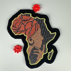 May include: Embroidered patch in the shape of Africa with a black outline and yellow stitching. The patch features a profile of a person with a beard and a head covering. Two small red flower-shaped embellishments are also present.
