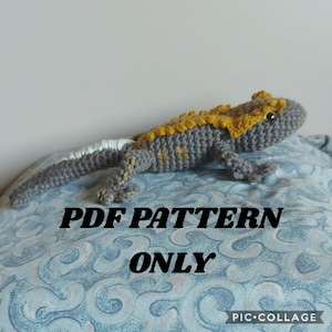 May include: Crochet pattern for a grey and yellow lizard. The pattern is available as a PDF download. The image shows the finished crocheted lizard.