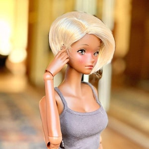 May include: A doll with a light brown complexion and blonde hair wearing a gray tank top and black leather pants.