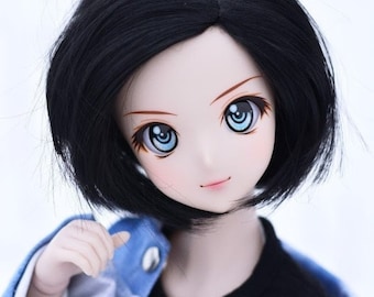 May include: A doll with black hair and large blue eyes. The doll is wearing a black t-shirt with Japanese text and a blue jacket. The doll's face is pale with pink lips.