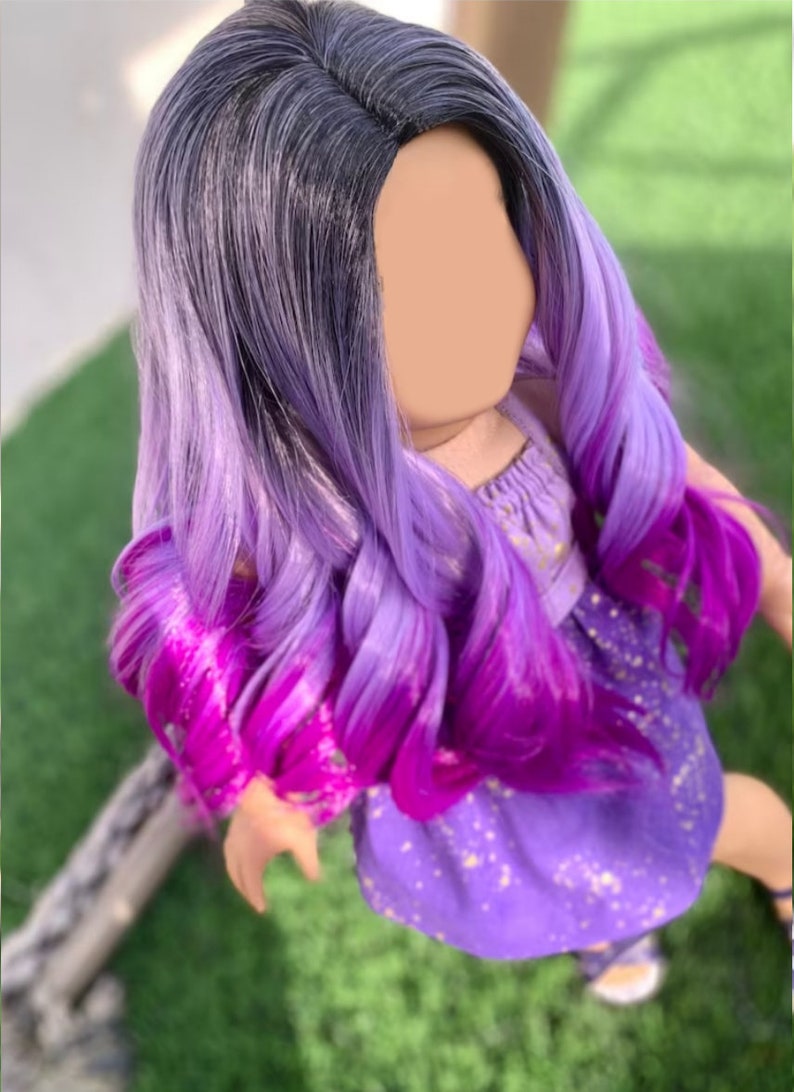 May include: A doll with a wig featuring a dark to light purple ombre. The wig has long, wavy curls with a vibrant magenta at the tips. The doll is wearing a purple dress with gold star accents.