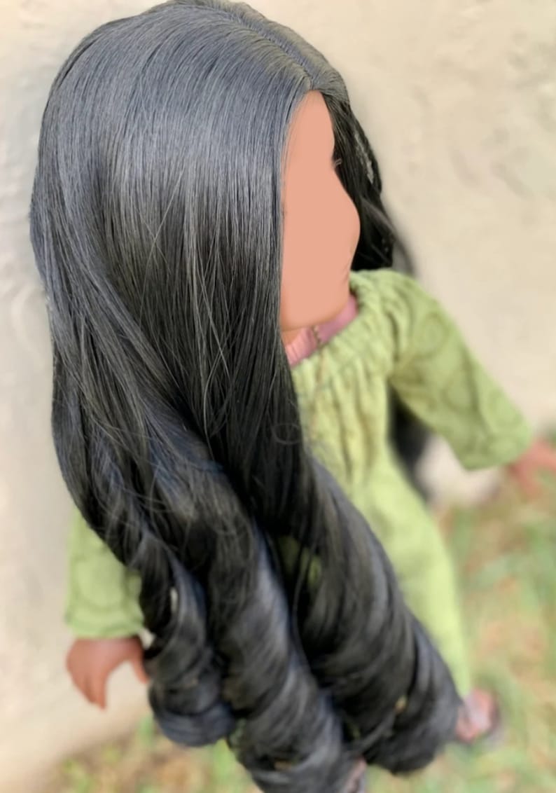 May include: A doll with long, black, wavy hair wearing a green dress.
