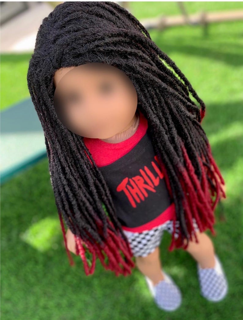 May include: A doll with black dreadlocks that fade to red at the ends. The doll is wearing a red and black shirt with the word "THRILL" in red, checkered shorts, and grey and white checkered slip-on shoes.