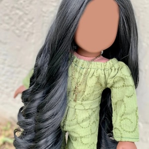 May include: A doll with long black hair wearing a green dress with a key necklace.