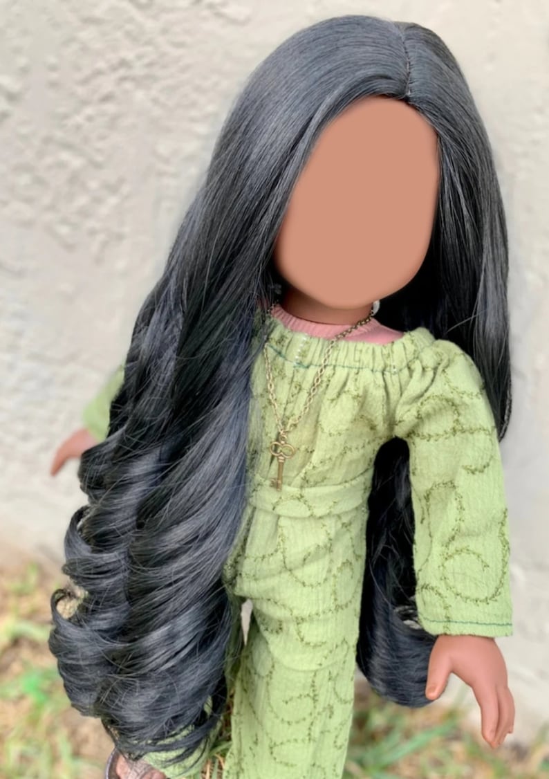 May include: A doll with long black hair wearing a green dress with a key necklace.